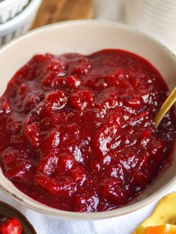 Orange Cranberry Sauce in a bowl with a gold spoon.