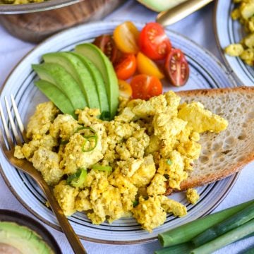 Tofu Scramble on a plate with a piece of toast and sliced avocado.