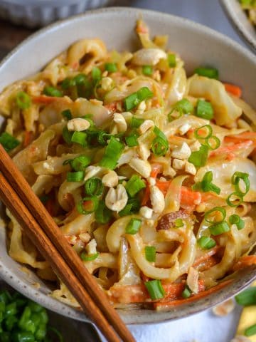 Vegan Peanut Udon Noodles in a bowl with chopsticks.