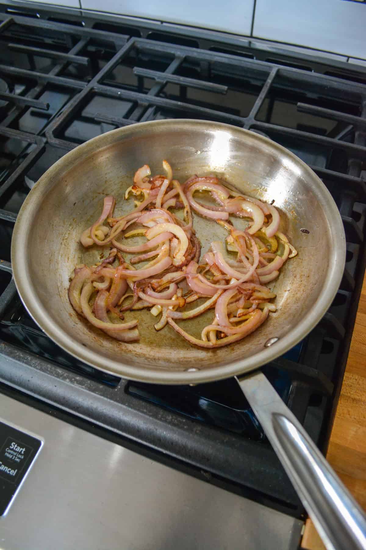 Onion sautéing in a stainless steel skillet.