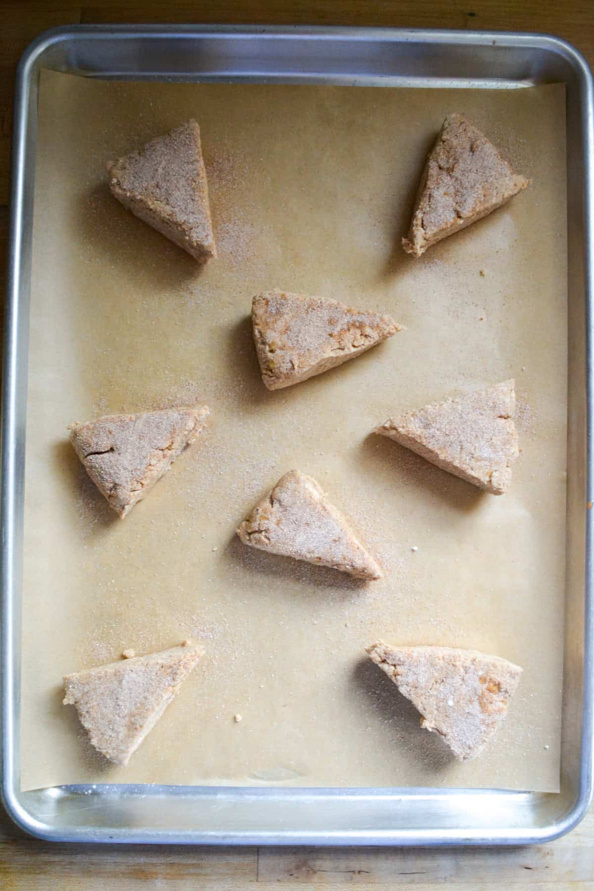 Scones on a baking sheet topped with cinnamon sugar.