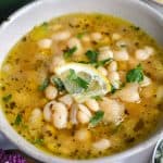 Brothy Great Northern Beans in a bowl topped with a slice of lemon.