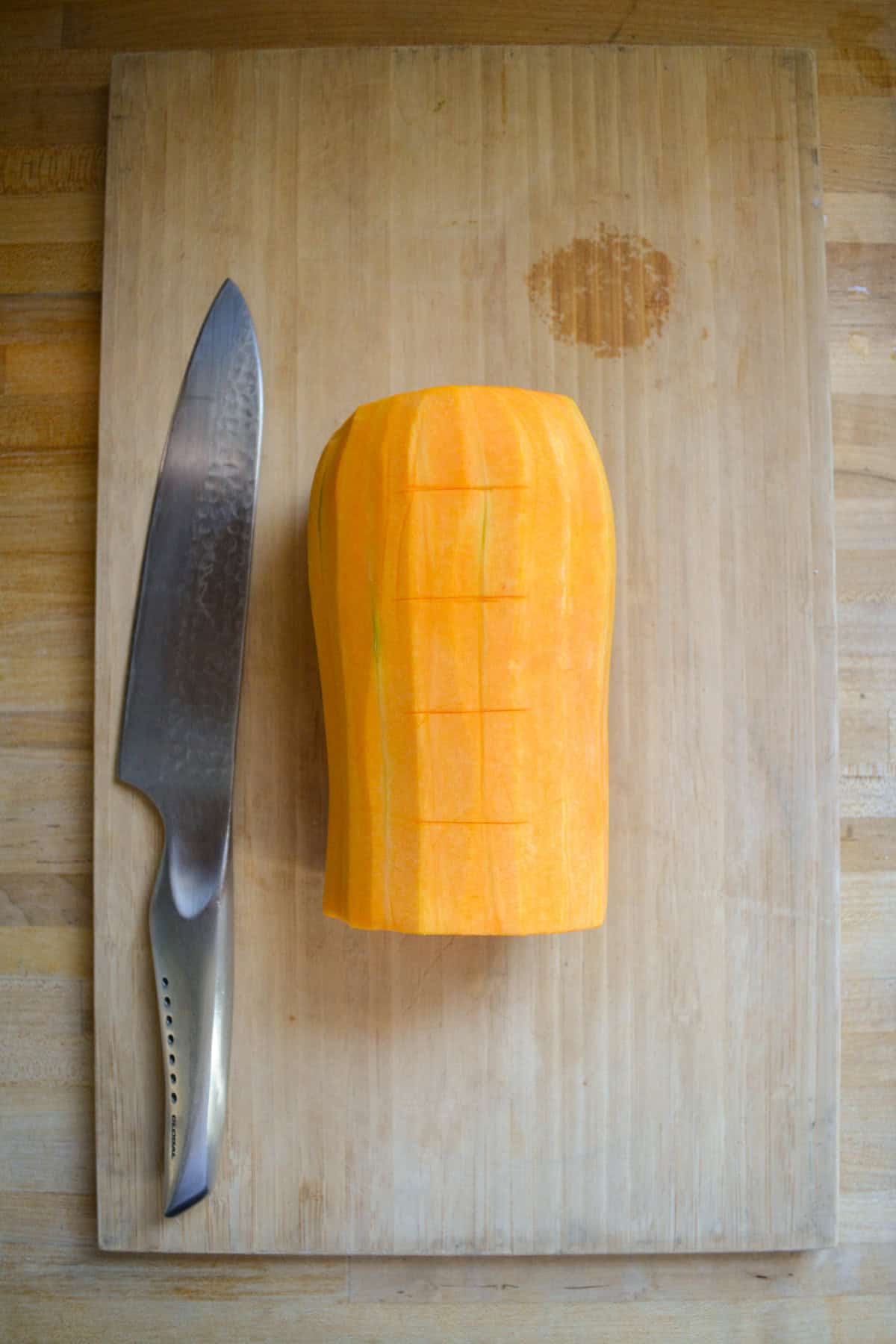 The top of a butternut squash that has been peeled on a cutting board.