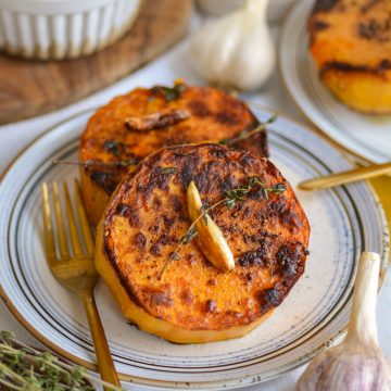 Butternut Squash Steaks on a small plate with a gold fork.