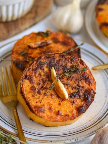 Butternut Squash Steaks on a small plate with a gold fork.