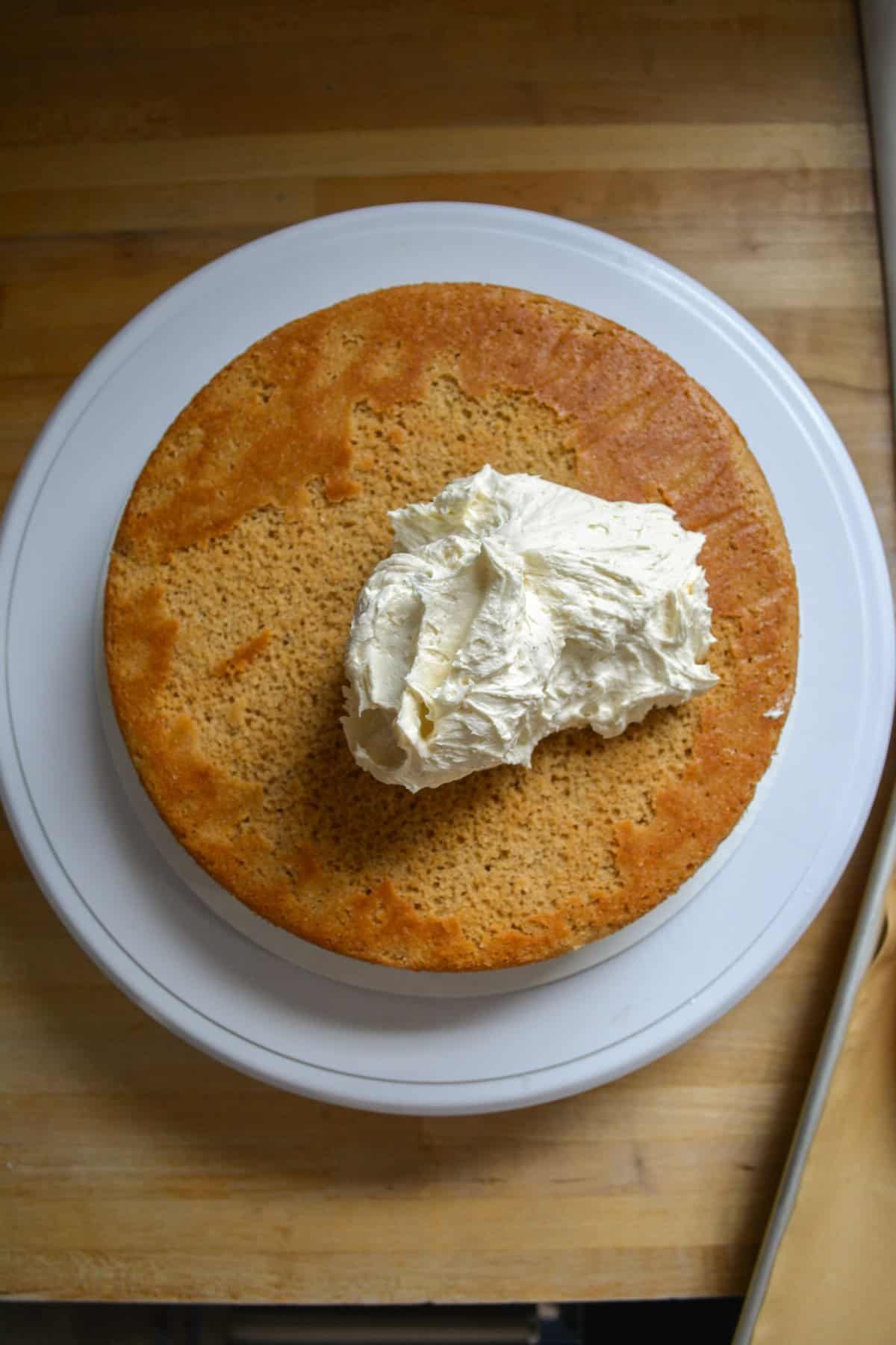 An Earl Grey Lavender Cake layer on a cake board with frosting on top.