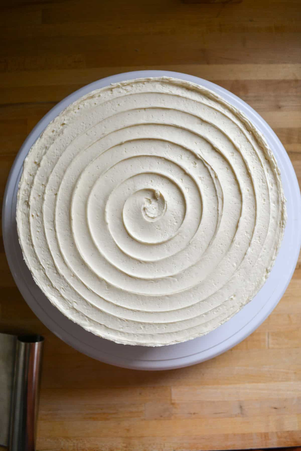 A cake that is frosted with vanilla bean buttercream in a spiral design.