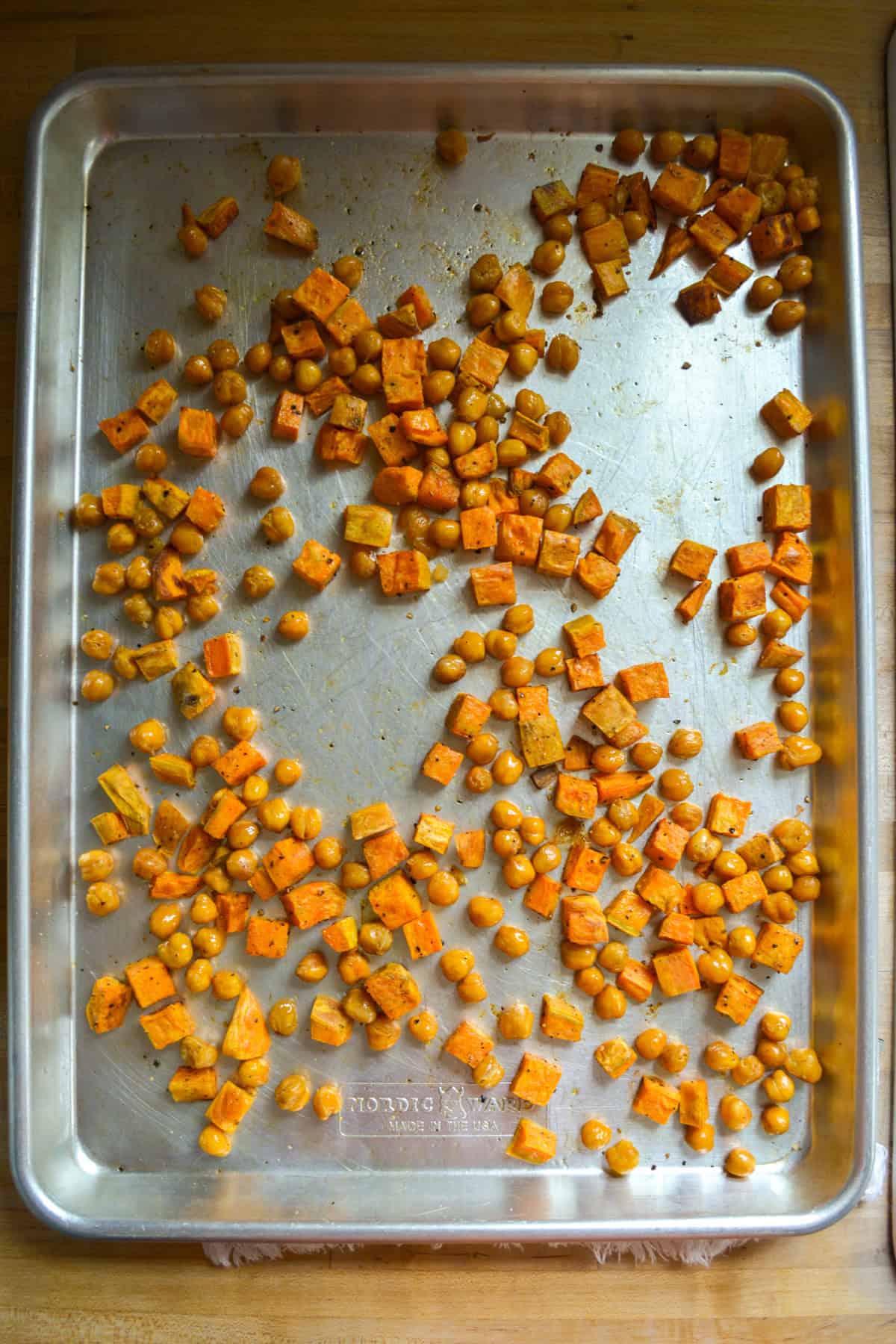 Roasted chickpeas and sweet potatoes on a baking sheet.