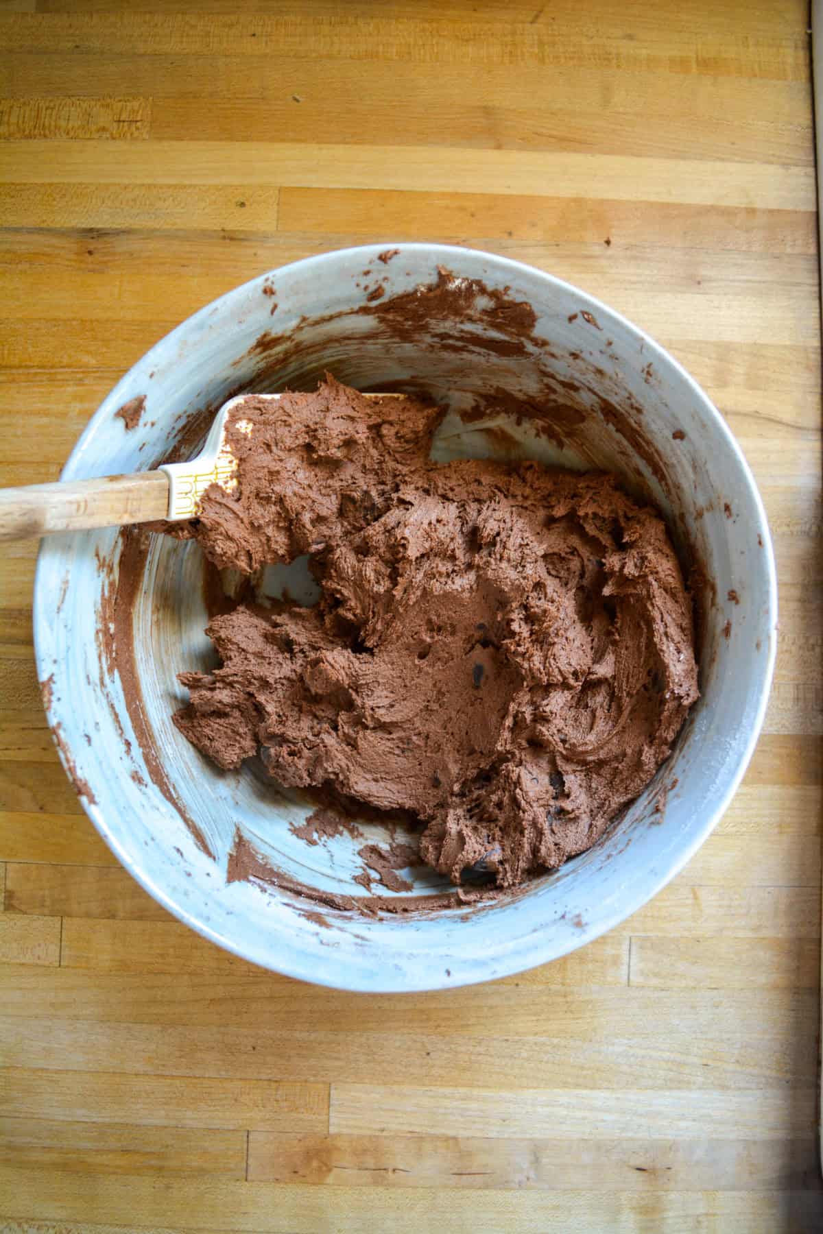 Vegan double chocolate cookie dough in a mixing bowl with a spatula.