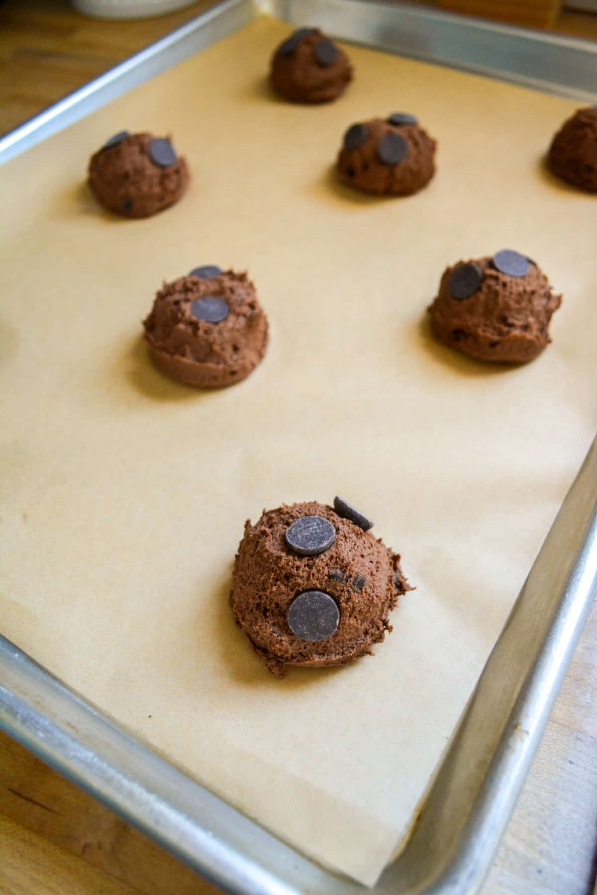Vegan Chocolate Chocolate Chip Cookies scooped onto a lined baking sheet.