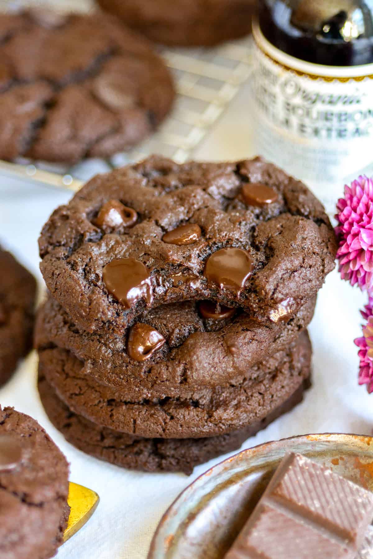 A stack of Vegan Chocolate Chocolate Chip Cookies with a bite taken out of the top cookie.