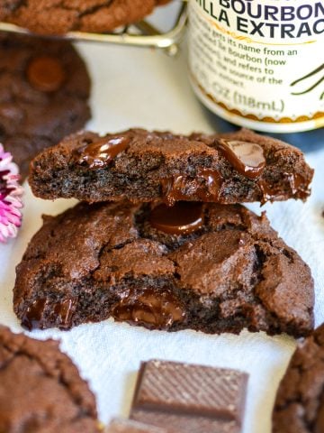 A Vegan Chocolate Chocolate Chip Cookies that is broken in half on a linen cloth.