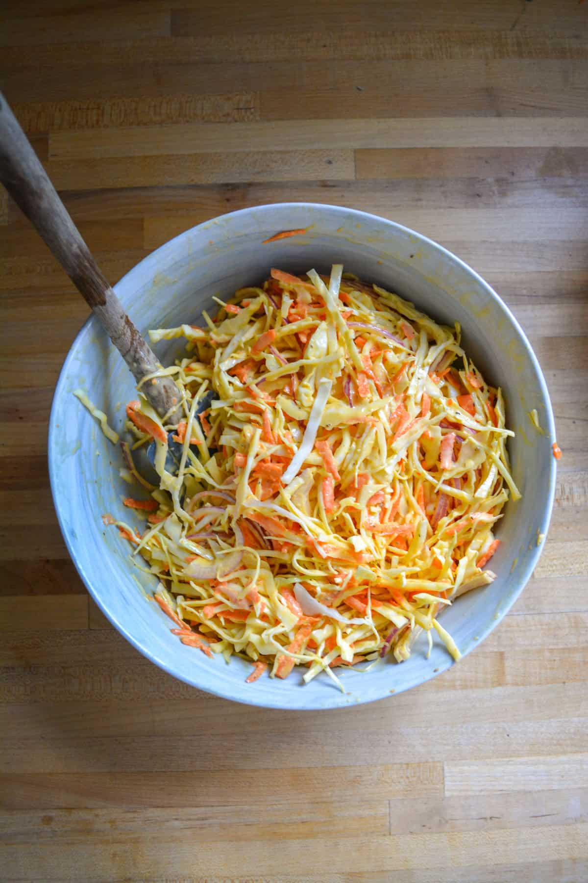Coleslaw tossed together in a large bowl.