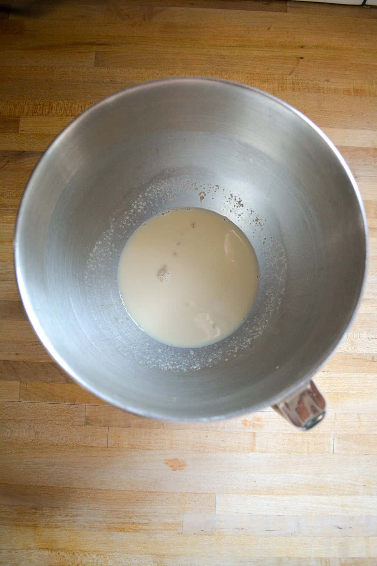 Milk and yeast in the bowl of a stand mixer.