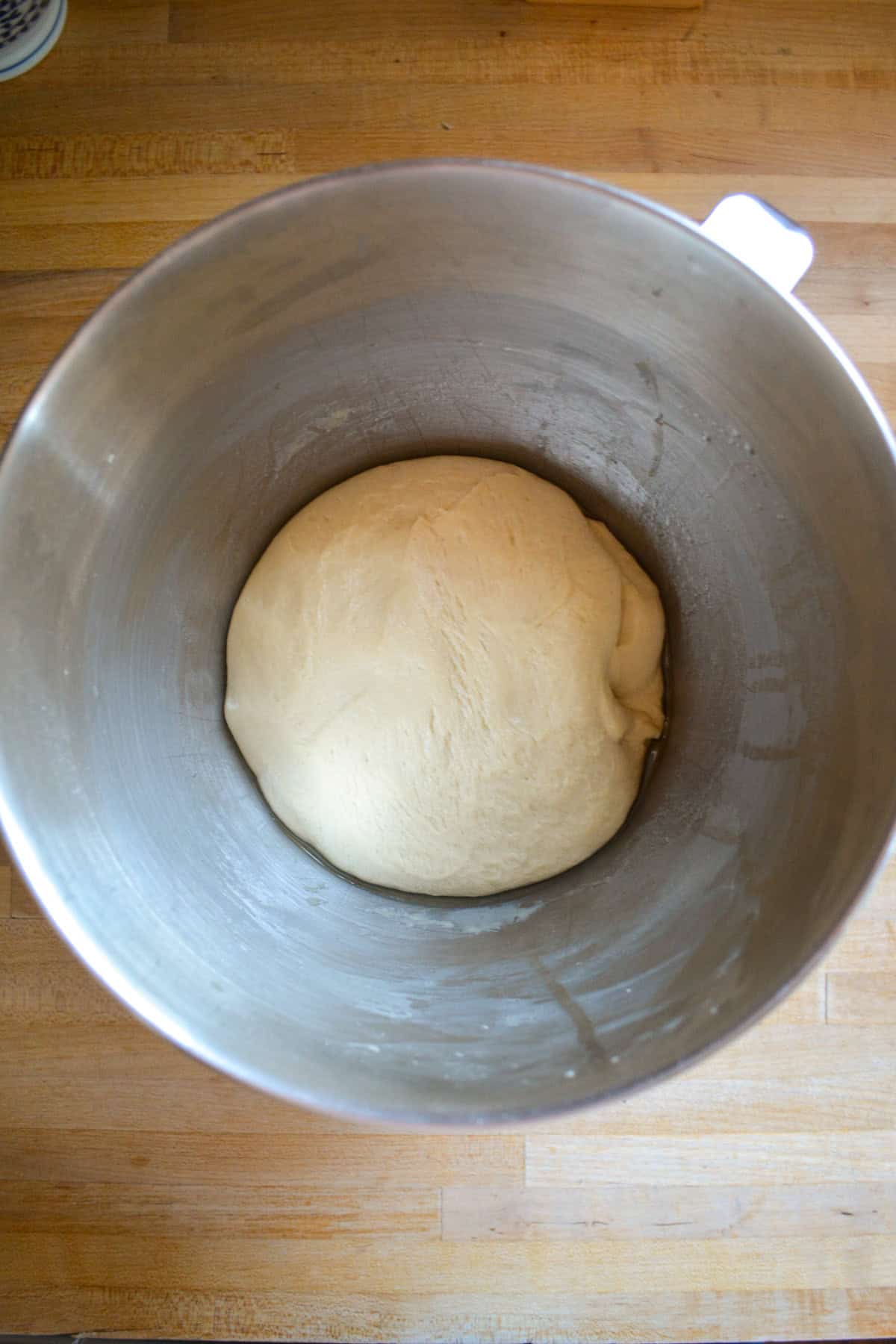 Risen dough in a metal bowl.