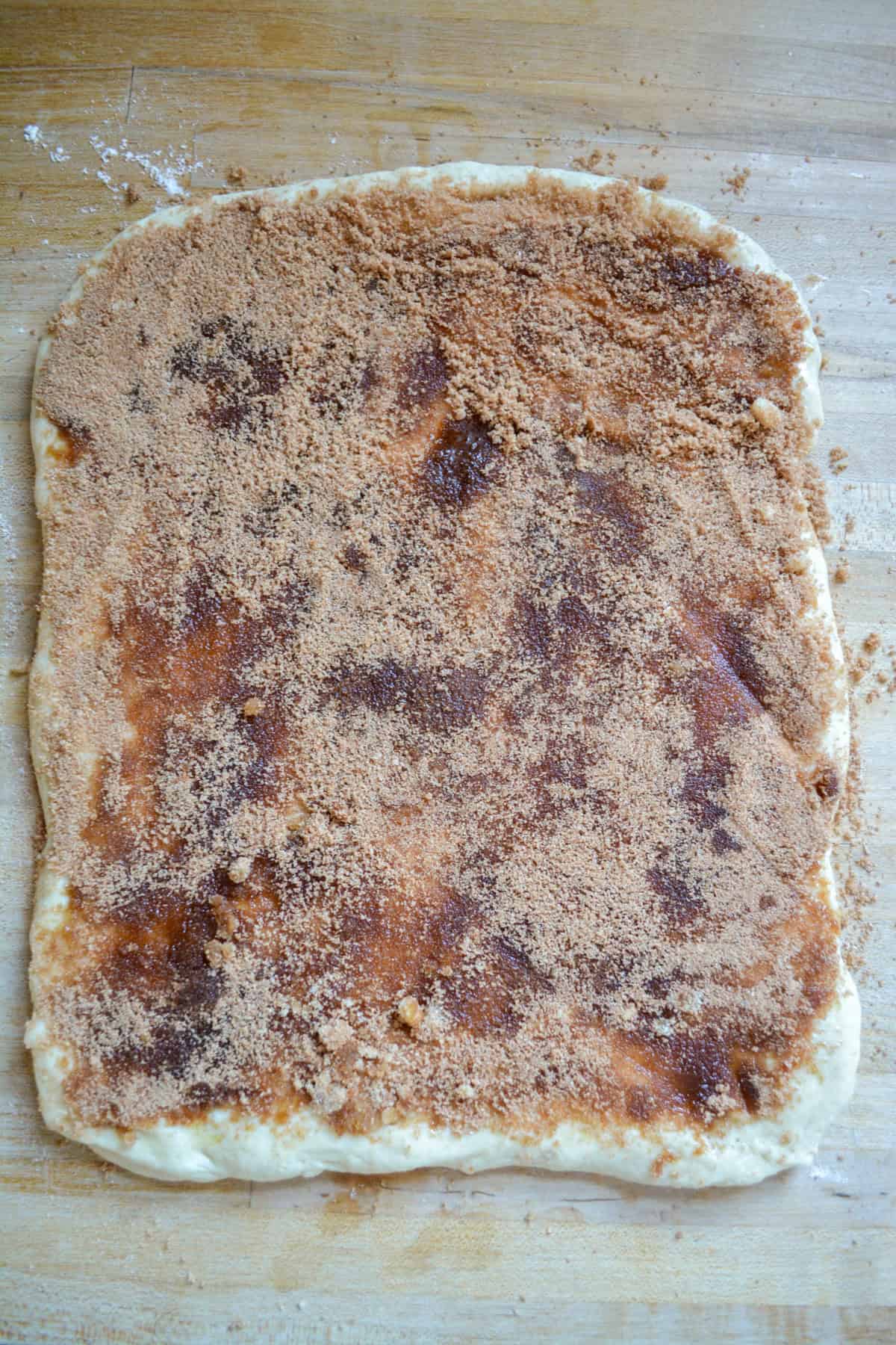 Cinnamon Roll Dough rolled out and topped with melted butter and brown sugar and cinnamon.