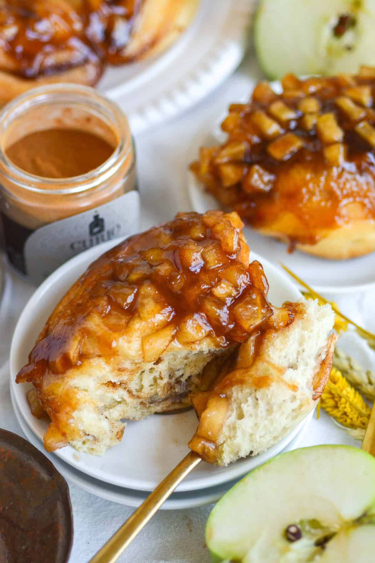 Apple Pie Cinnamon Roll on a small plate with a bite taken out of it.