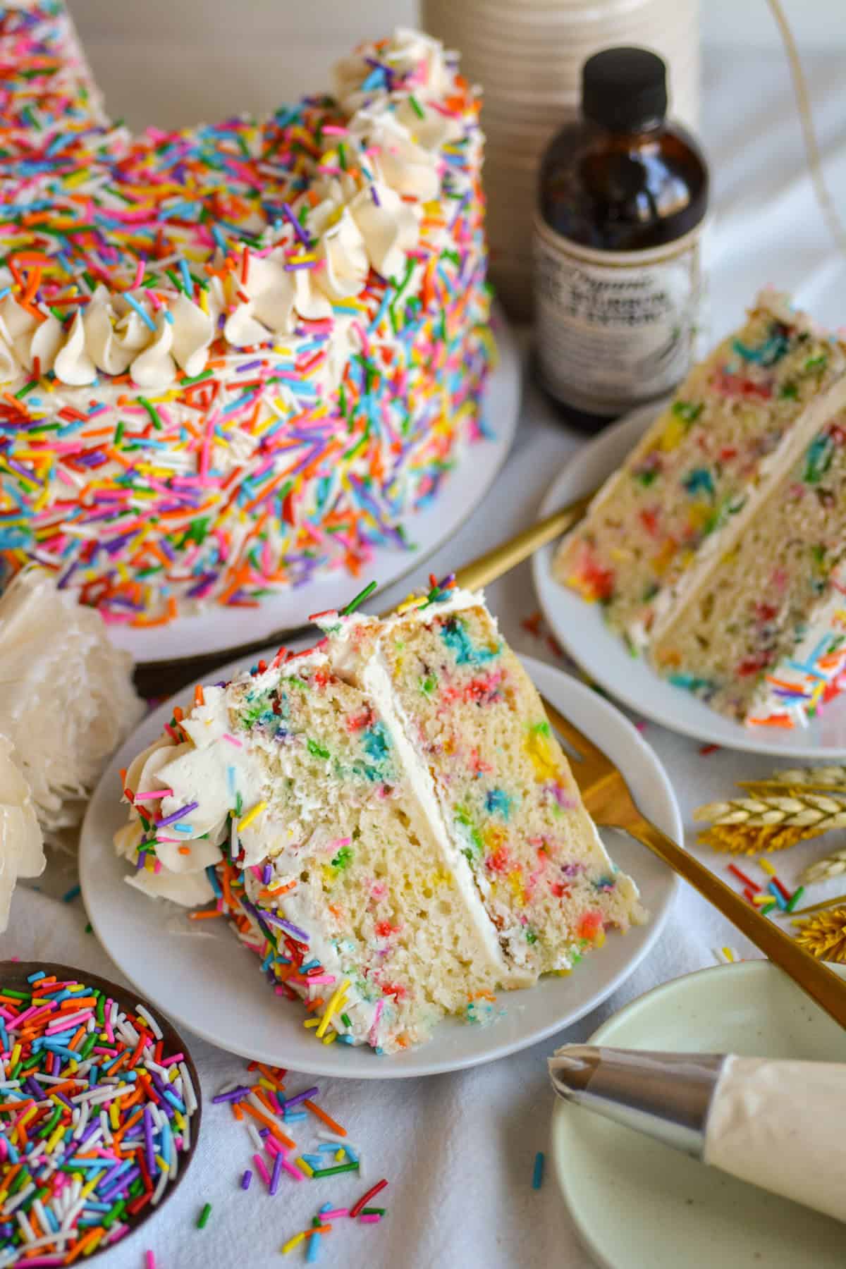 A slice of Vegan Funfetti Cake on a white plate on a linen cloth.