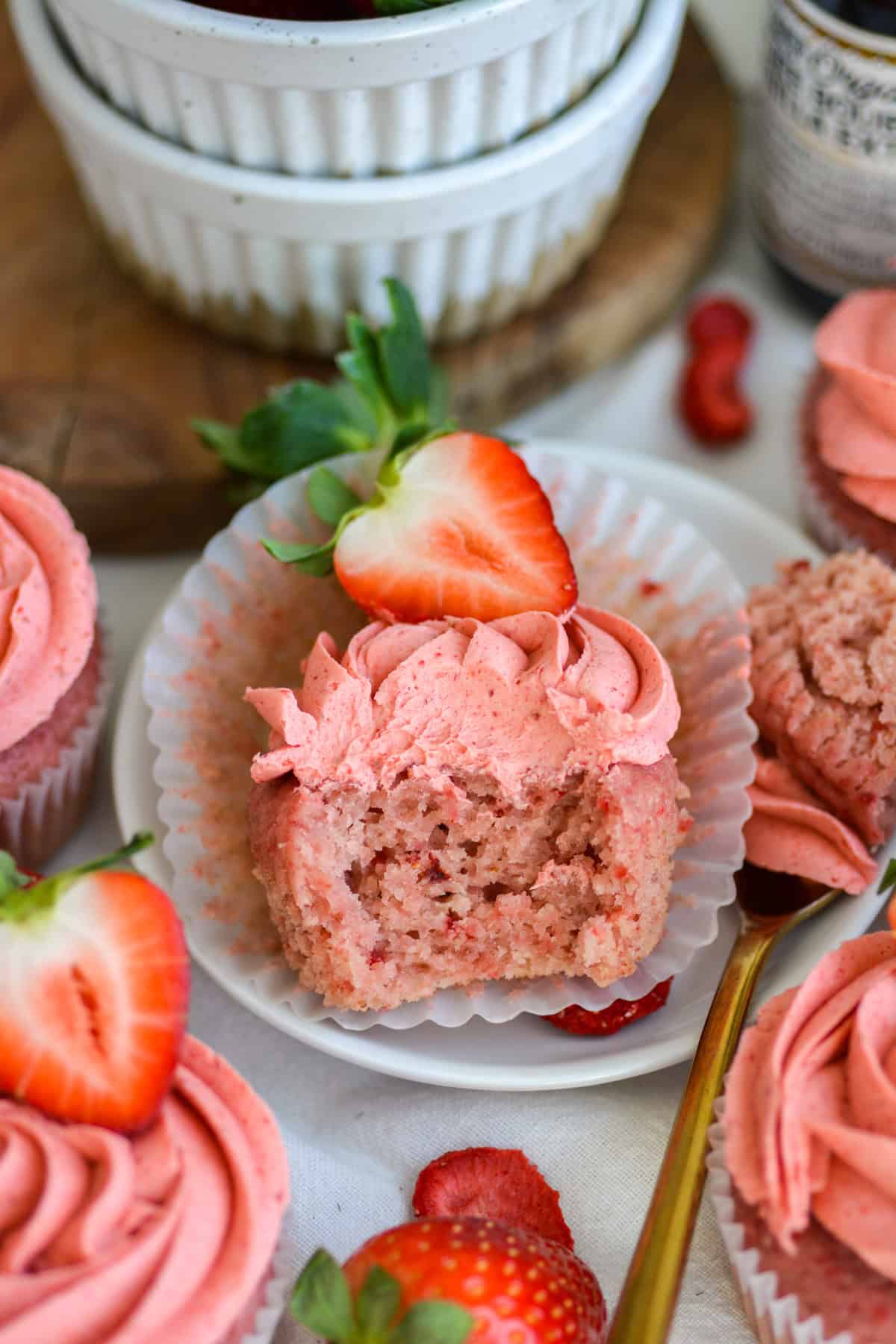 Vegan Strawberry Cupcake with a bite taken out of it on a small white plate.