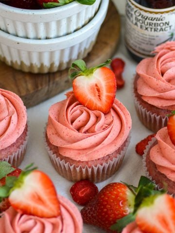 Vegan Strawberry Cupcakes on a linen cloth topped with a fresh strawberry.