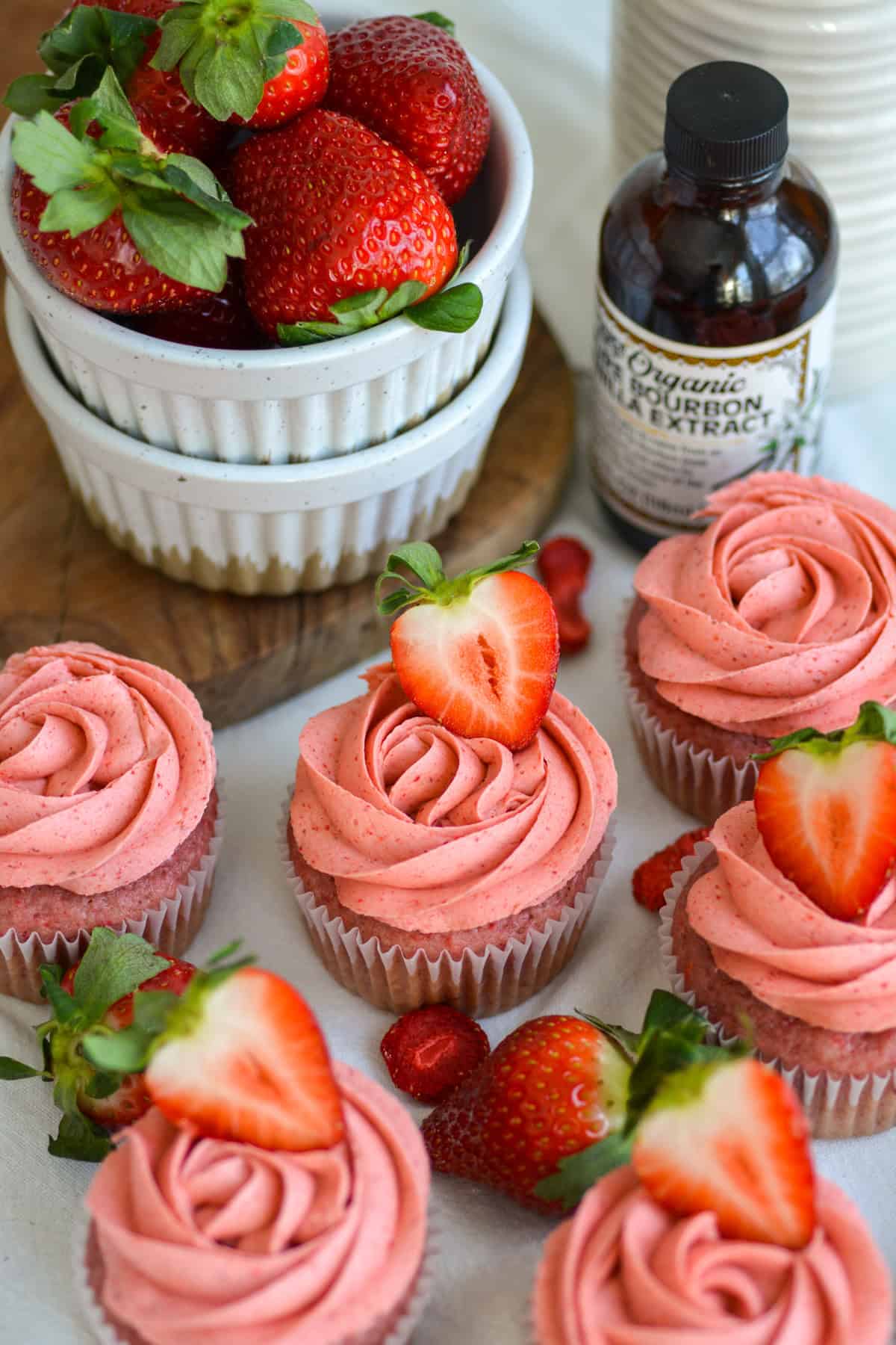 Vegan Strawberry Cupcakes topped with strawberries on a linen cloth.