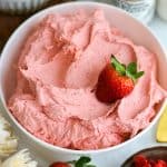 Vegan Strawberry Frosting in a bowl with a fresh strawberry on top.