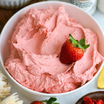 Vegan Strawberry Frosting in a bowl with a fresh strawberry on top.