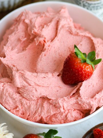 Vegan Strawberry Frosting in a bowl with a fresh strawberry on top.