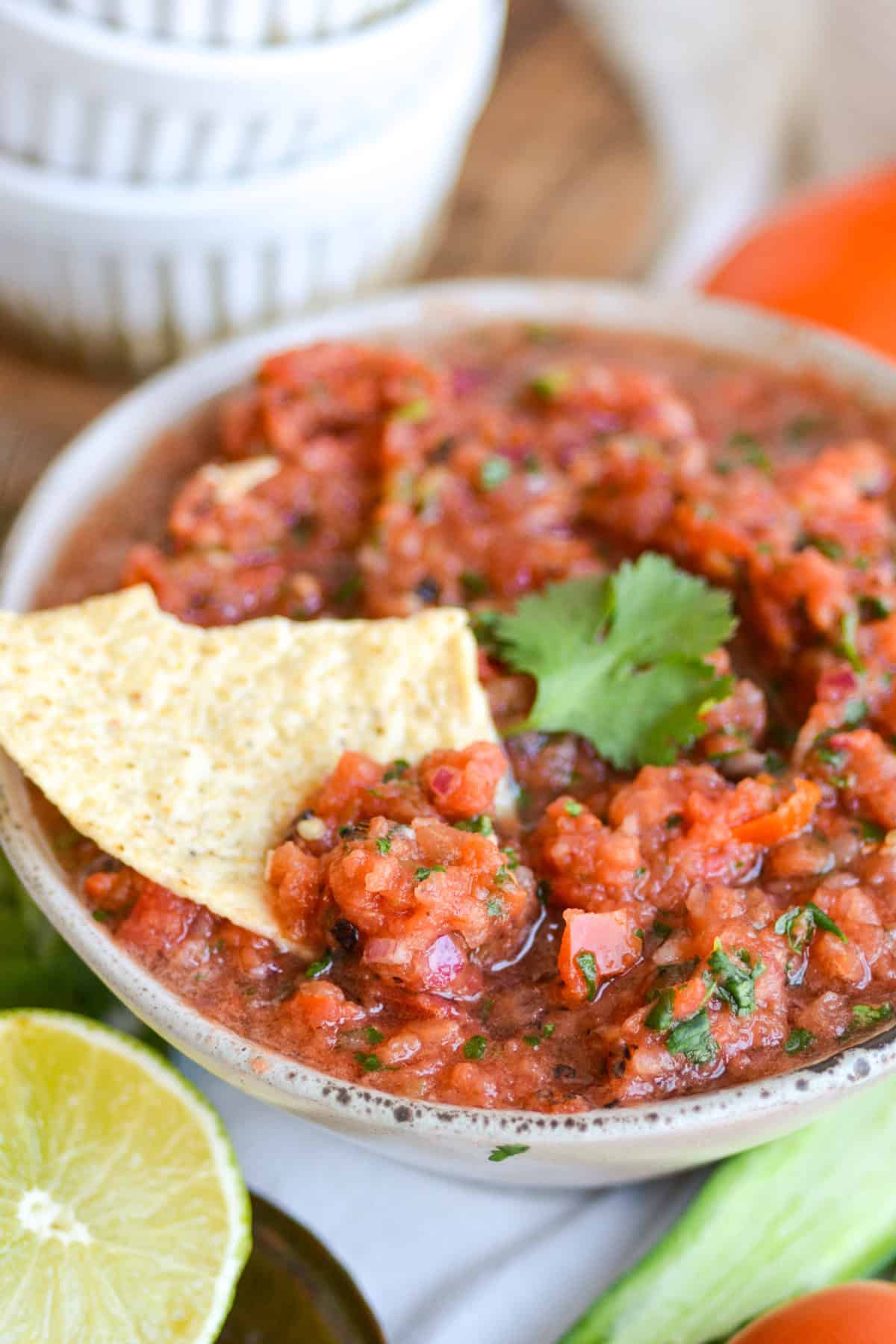 A chip dipped into homemade Vitamix blender salsa in a bowl.