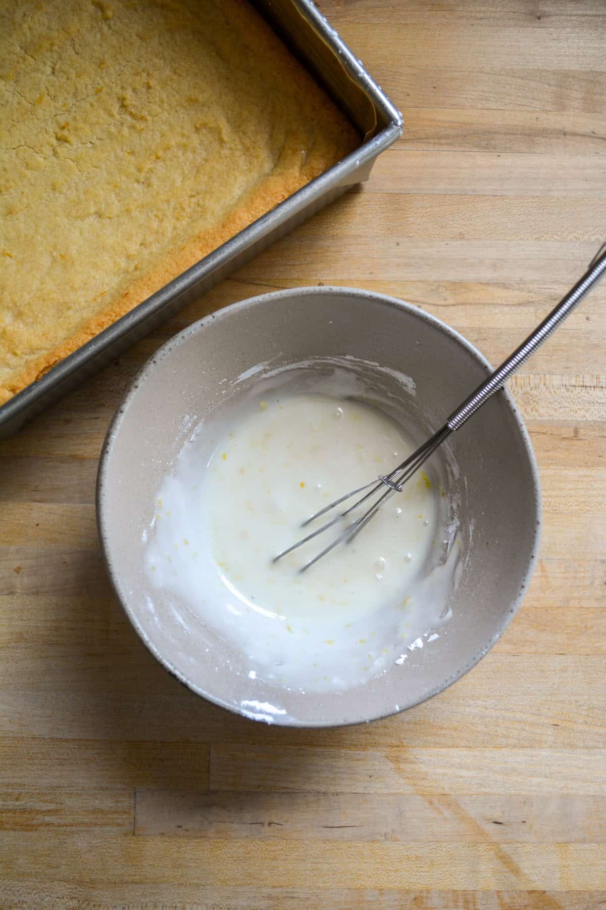Lemon glaze in a small bowl with a whisk.