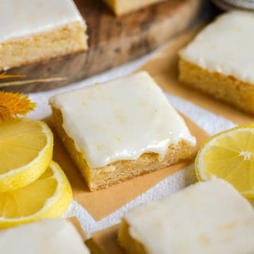A Lemon Cookie Bar topped with glaze on a linen surface.