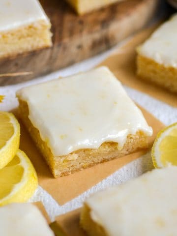 A Lemon Cookie Bar topped with glaze on a linen surface.