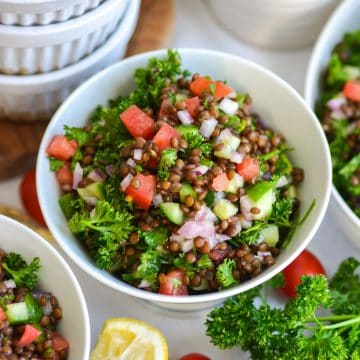 Mediterranean Black Lentil Salad in a bowl with chopped tomatoes, cucumber and parsley.
