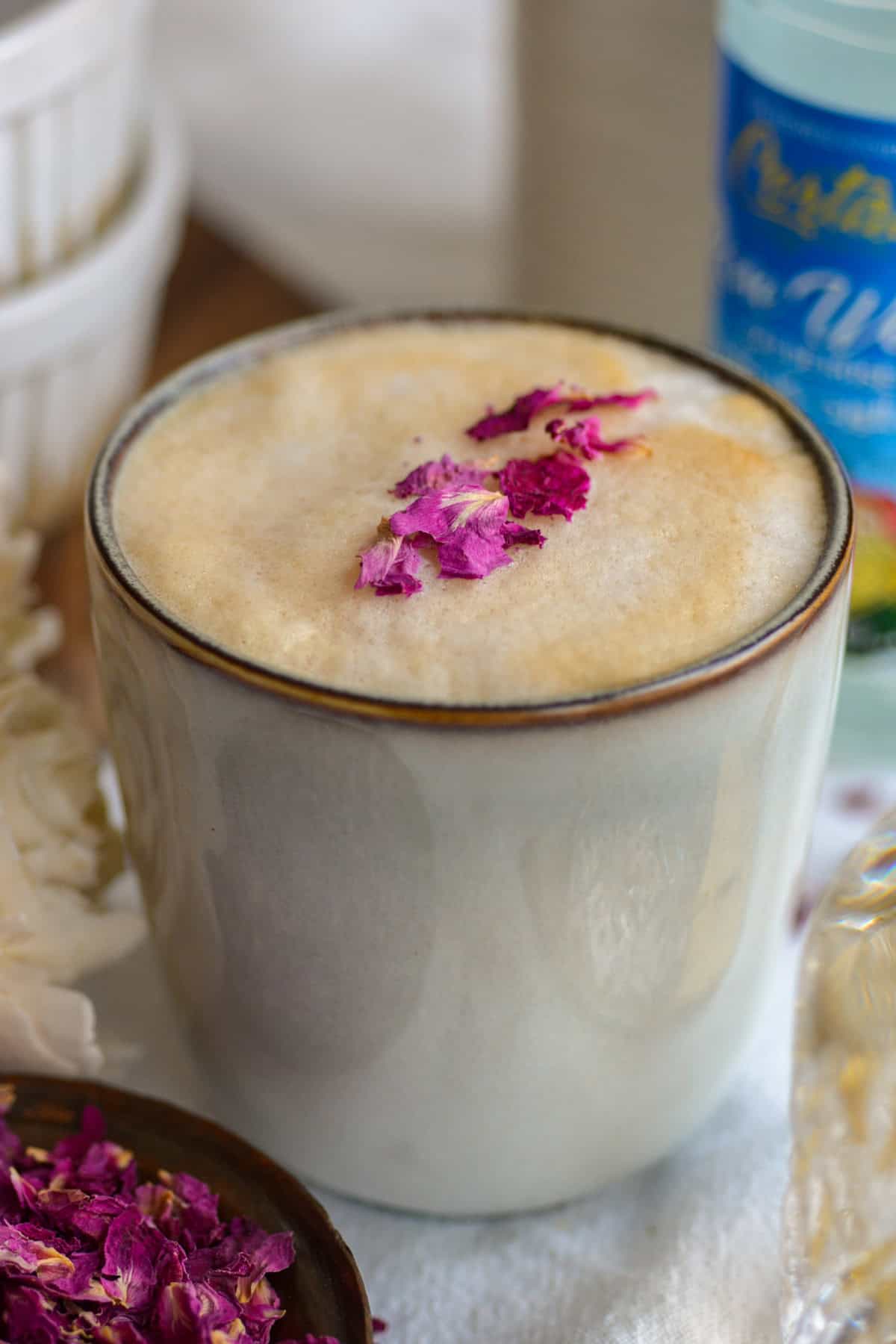 Rose Water Latte in a mug topped with dried rose petals.