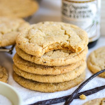A stack of vanilla bean cookies with a bite taken out of the top cookie.