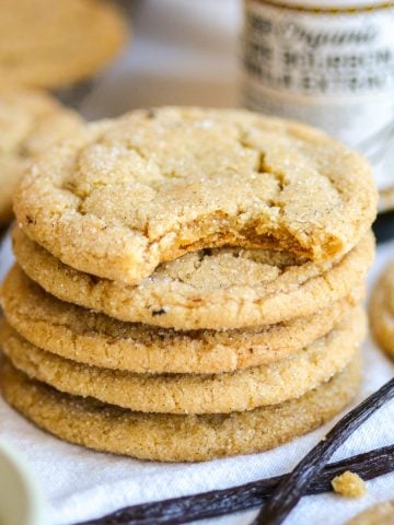 A stack of vanilla bean cookies with a bite taken out of the top cookie.