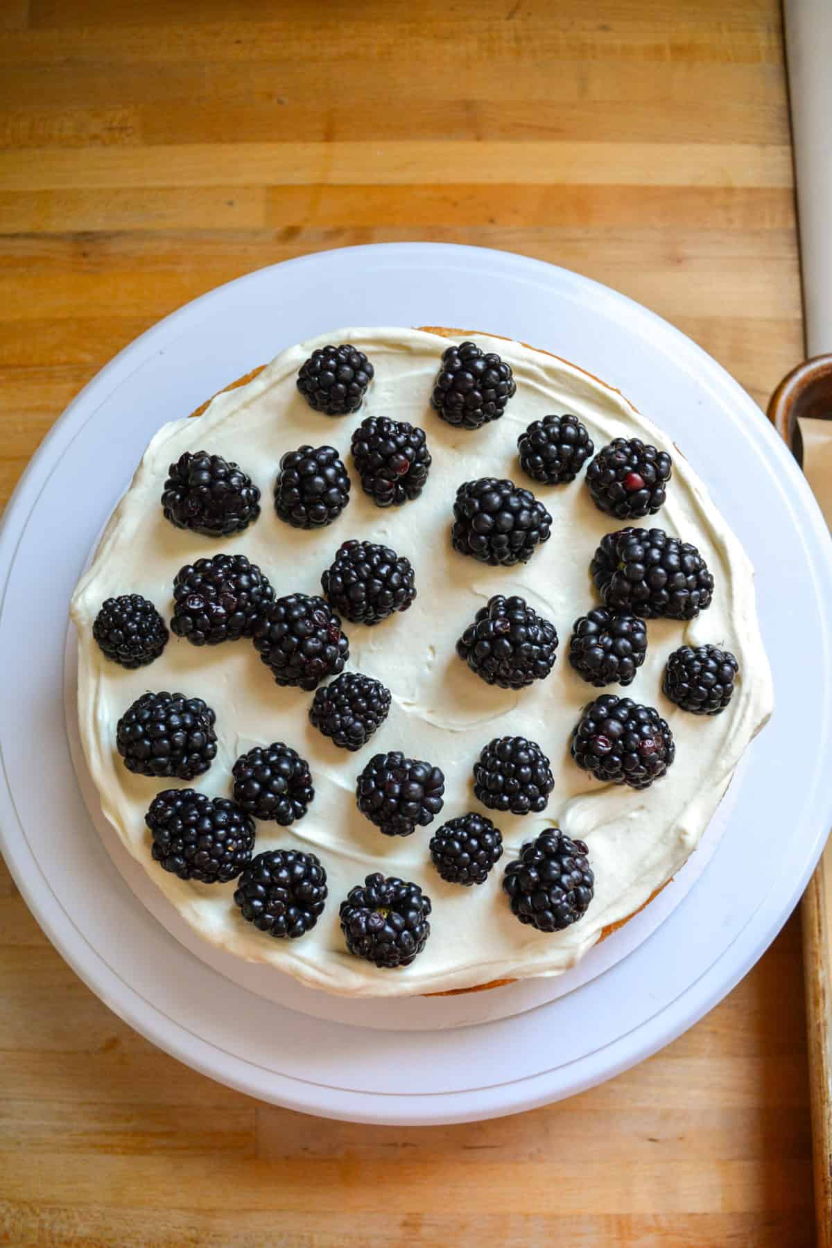 A cake layer topped with whipped cream and blackberries.