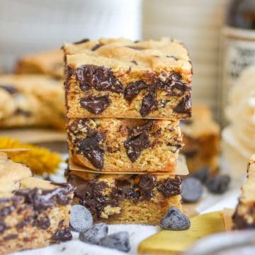 Three Vegan Blondies stacked on top of each other with chocolate chips scattered around.