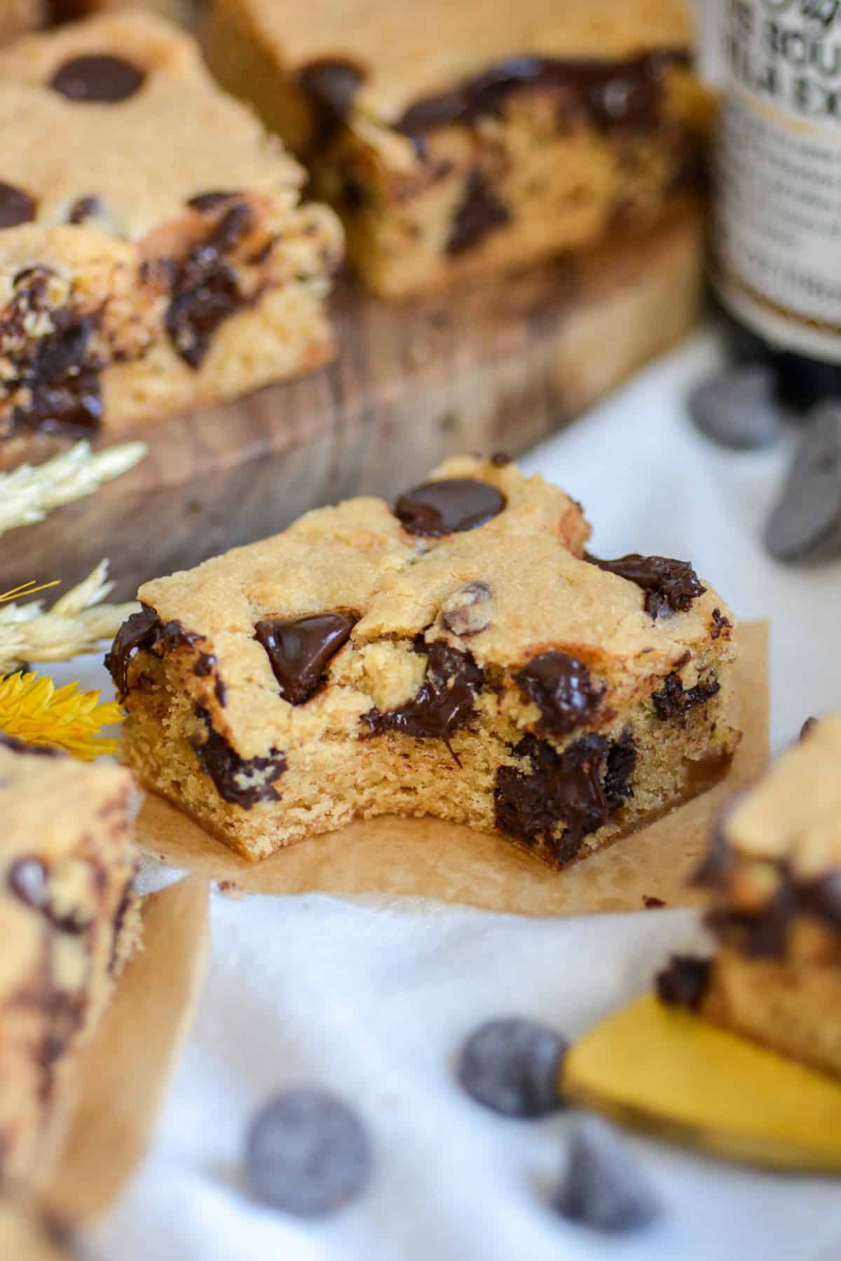 A slice of Vegan Blondie with a bite taken out of it on a linen cloth.