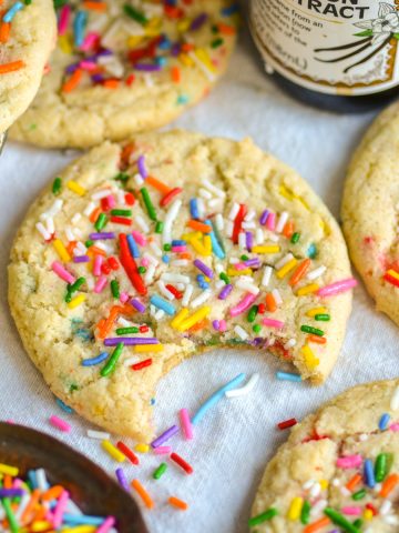 A bite taken out of a Vegan Funfetti Cookie on a linen cloth.