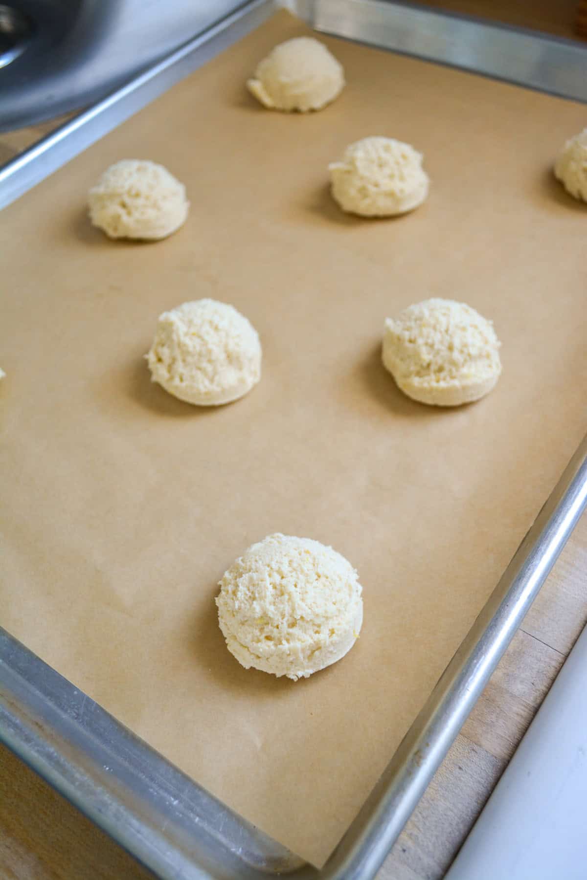 Cookie dough scooped onto a lined cookie sheet.
