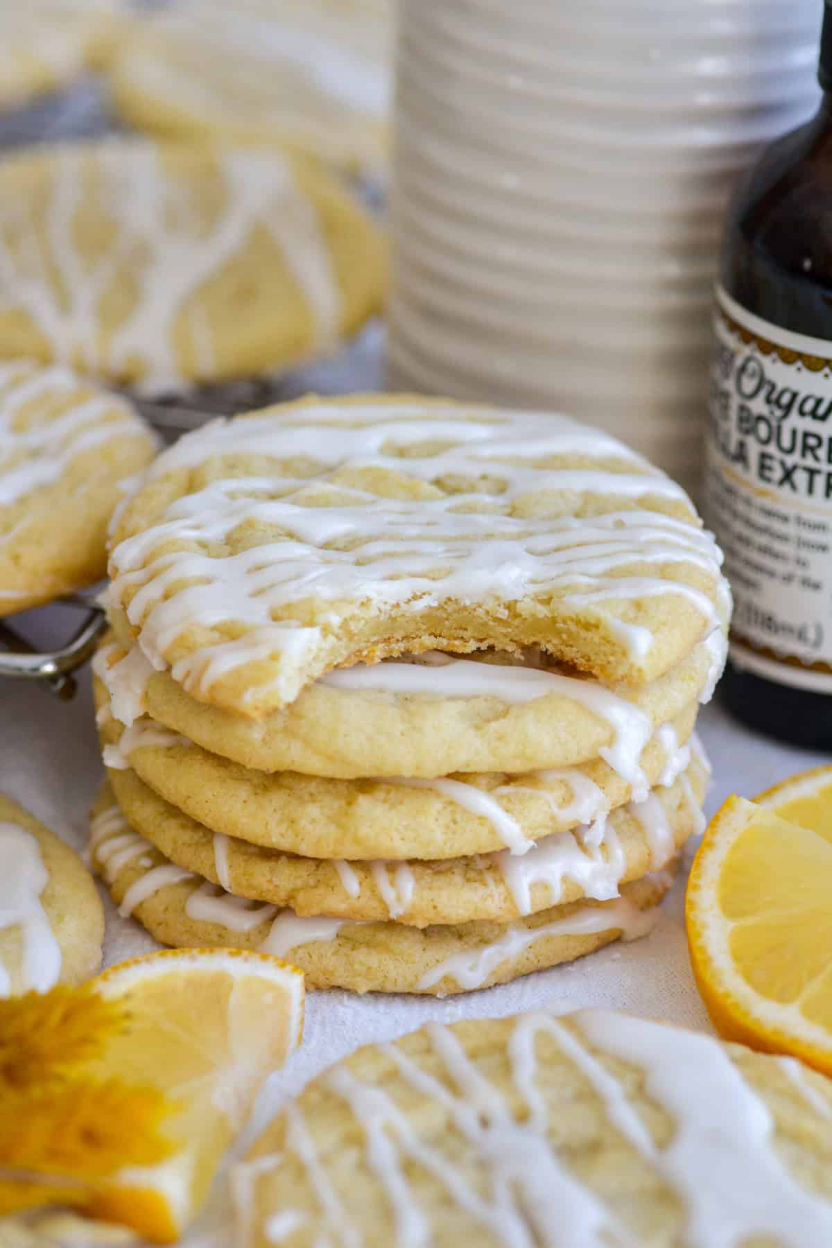 A stack of vegan lemon cookies with a bite taken out of the top cookie.
