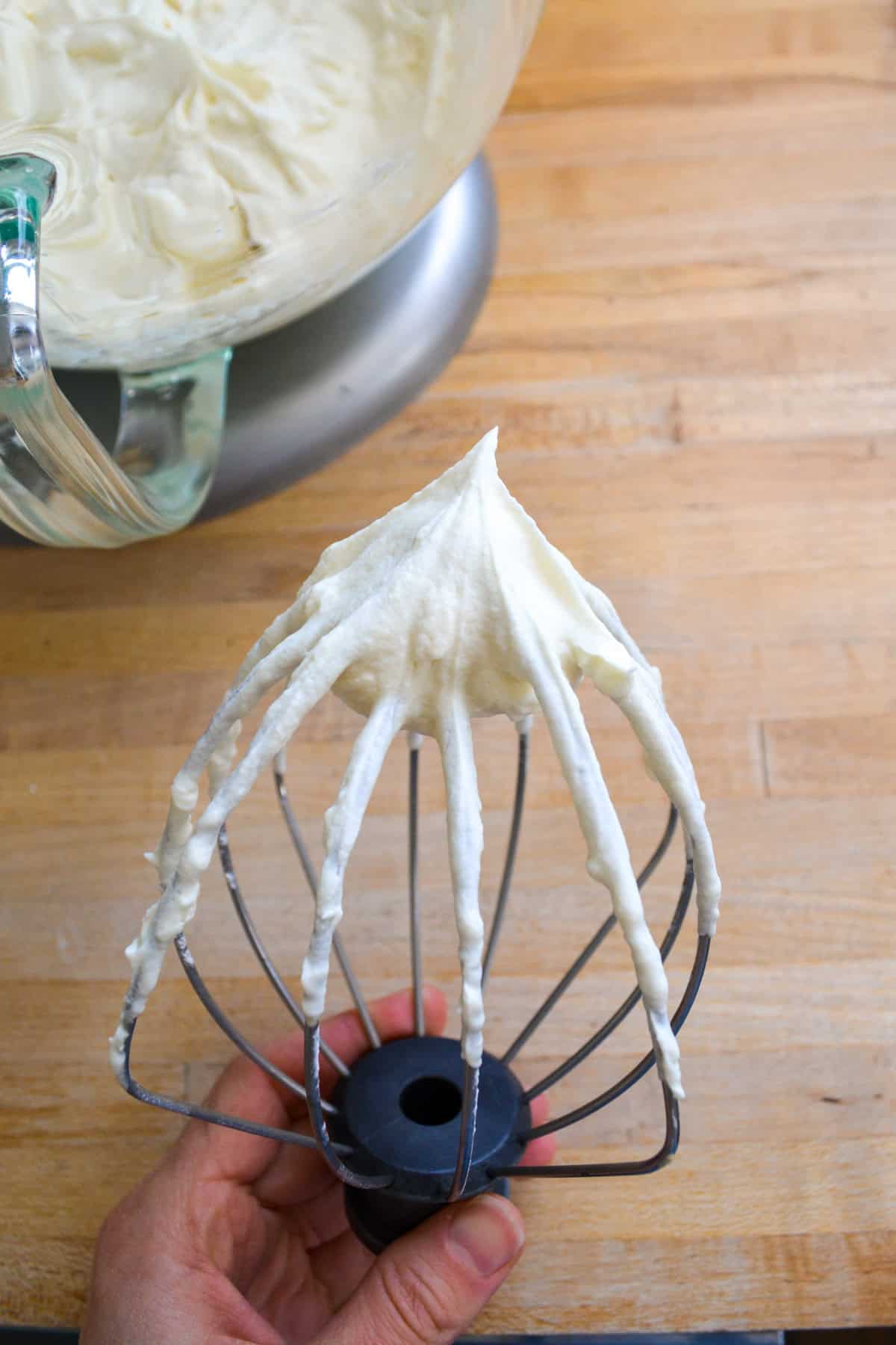 A whisk attachment with vegan whipped cream on it.