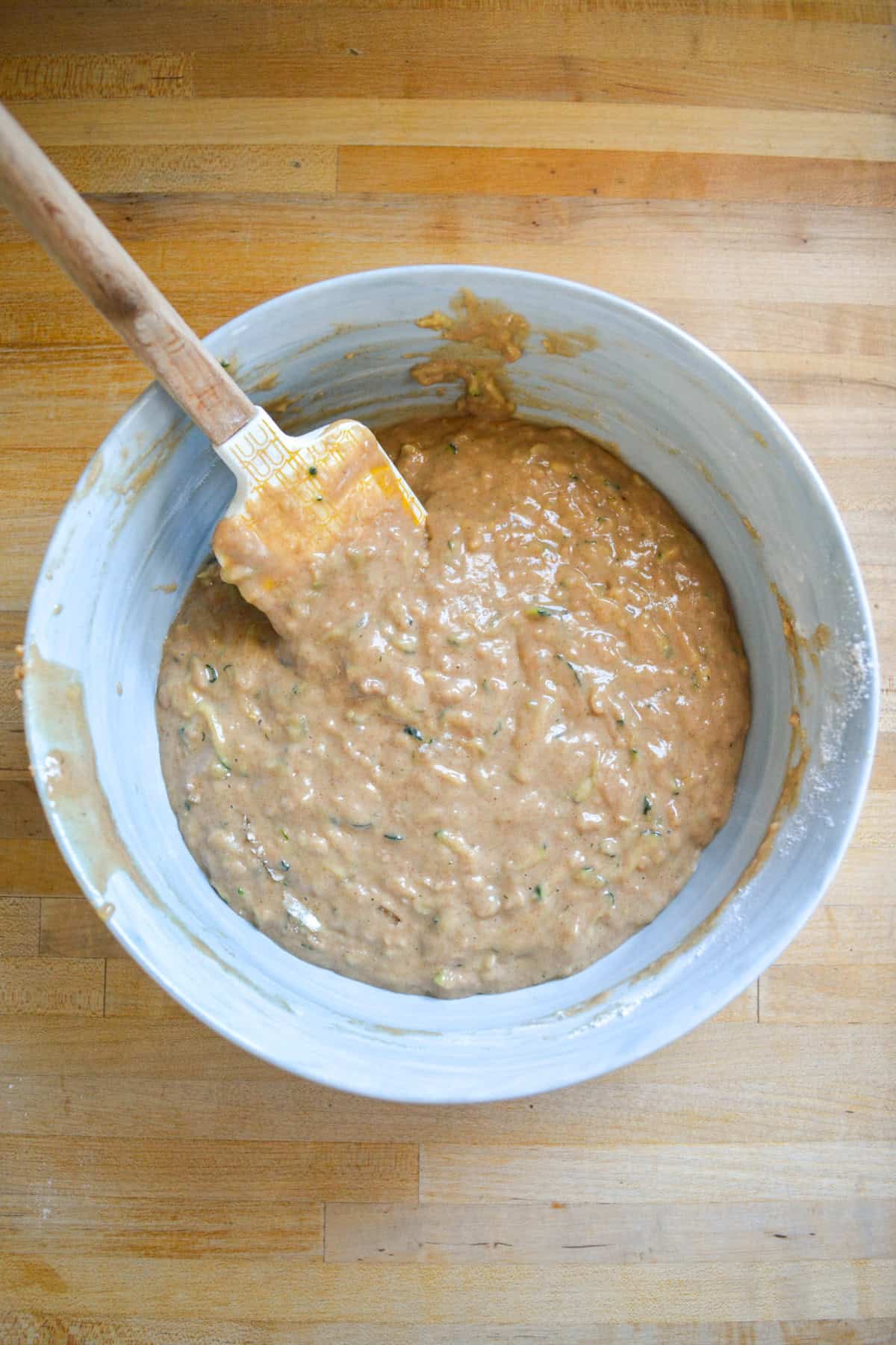 Muffin batter in a large mixing bowl with a rubber spatula.