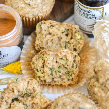 A Vegan Zucchini Muffin that is cut in half on a parchment paper liner.