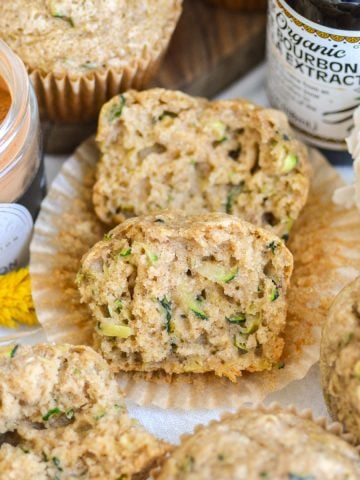 A Vegan Zucchini Muffin that is cut in half on a parchment paper liner.