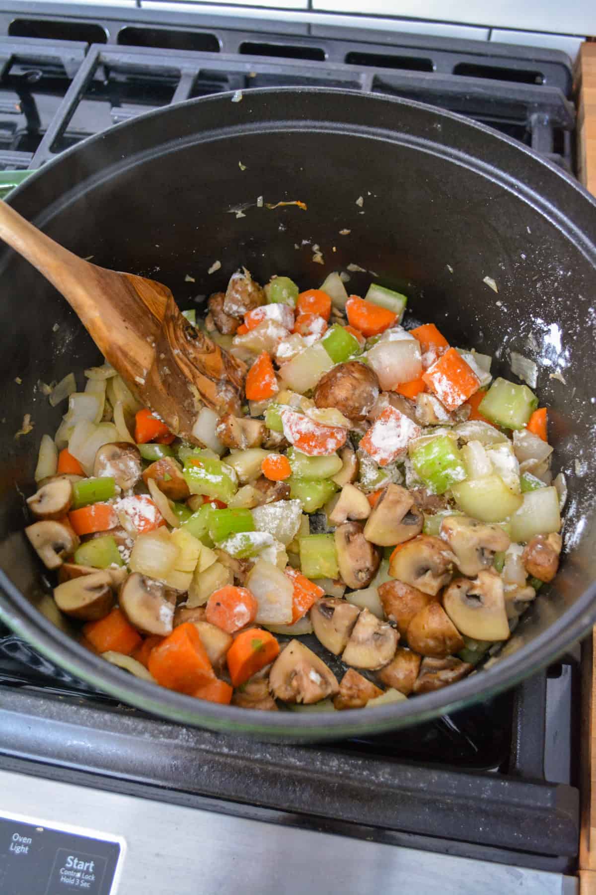 Flour sprinkled over vegetables in a large pot.