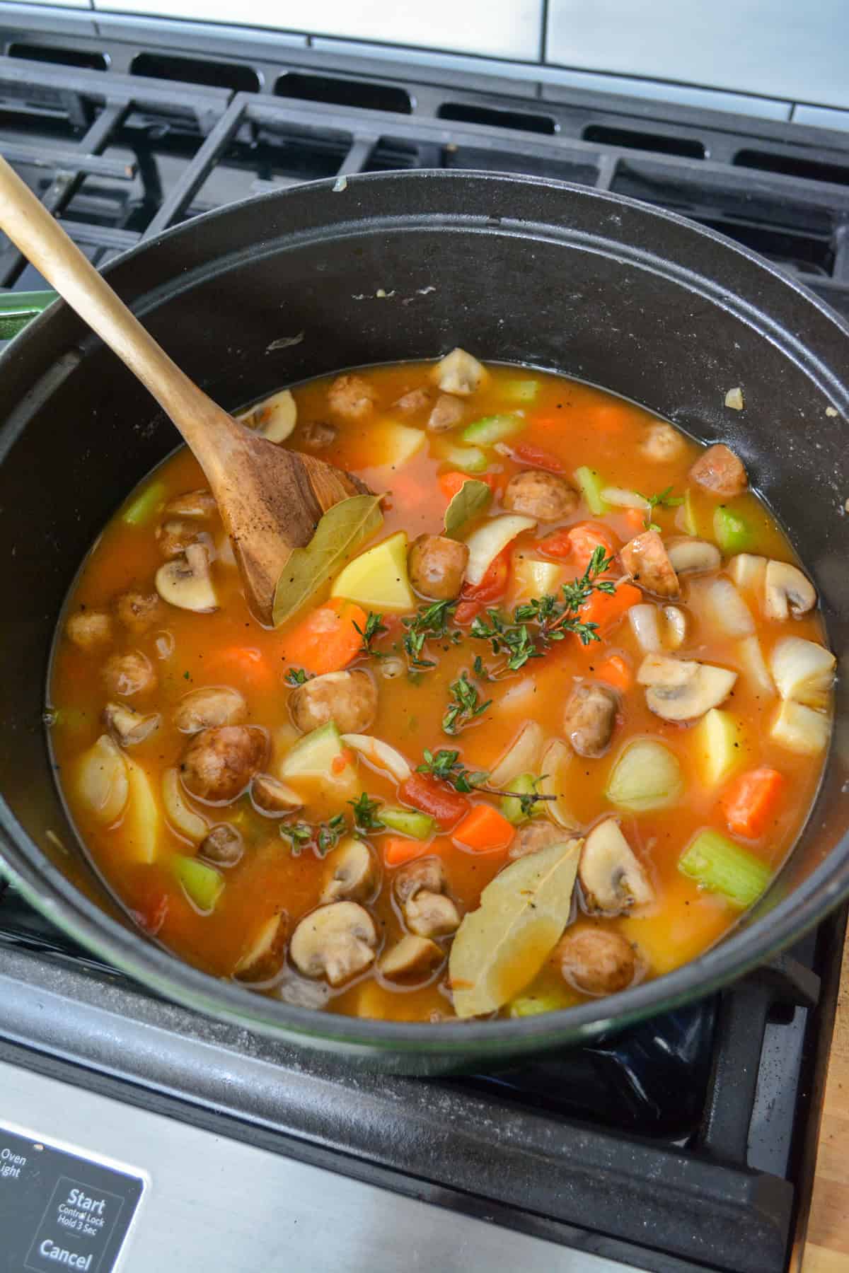 Broth and herbs added into the large pot of vegetables.