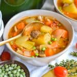 A bowl of Vegetable Stew with a gold spoon in it.