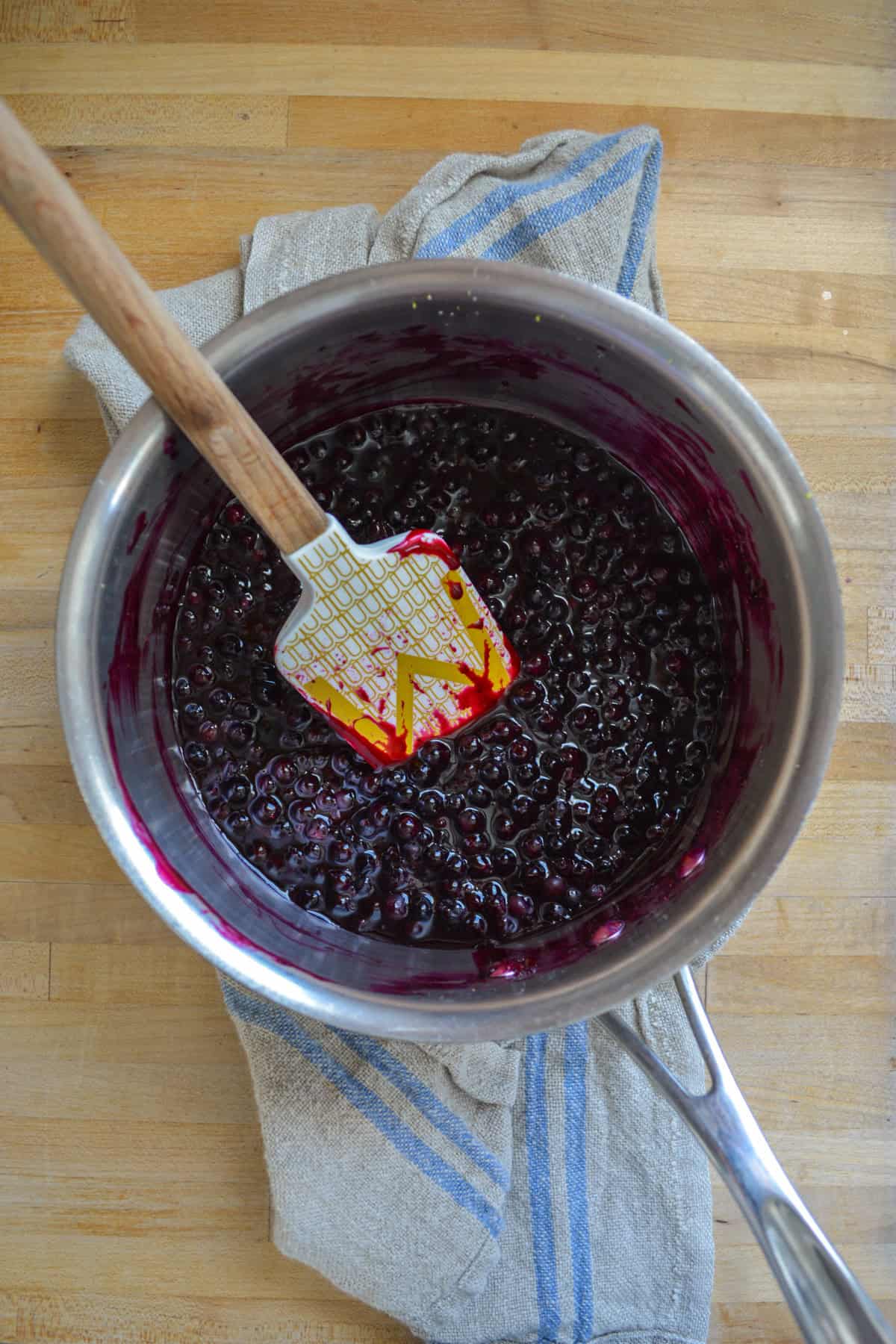 Blueberry filling in a pot on a wooden surface.